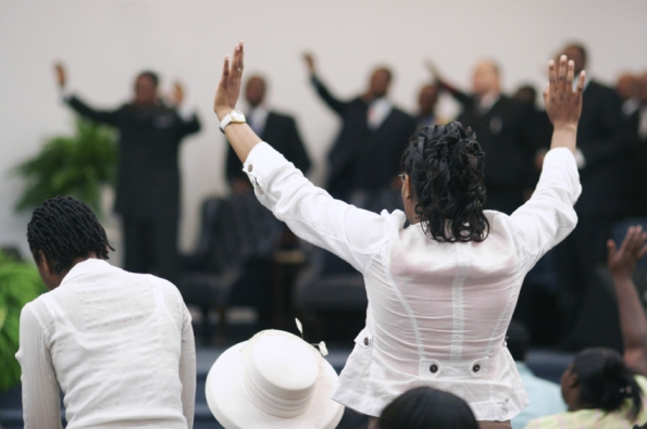 People in worship with hands raised pentecostal style.